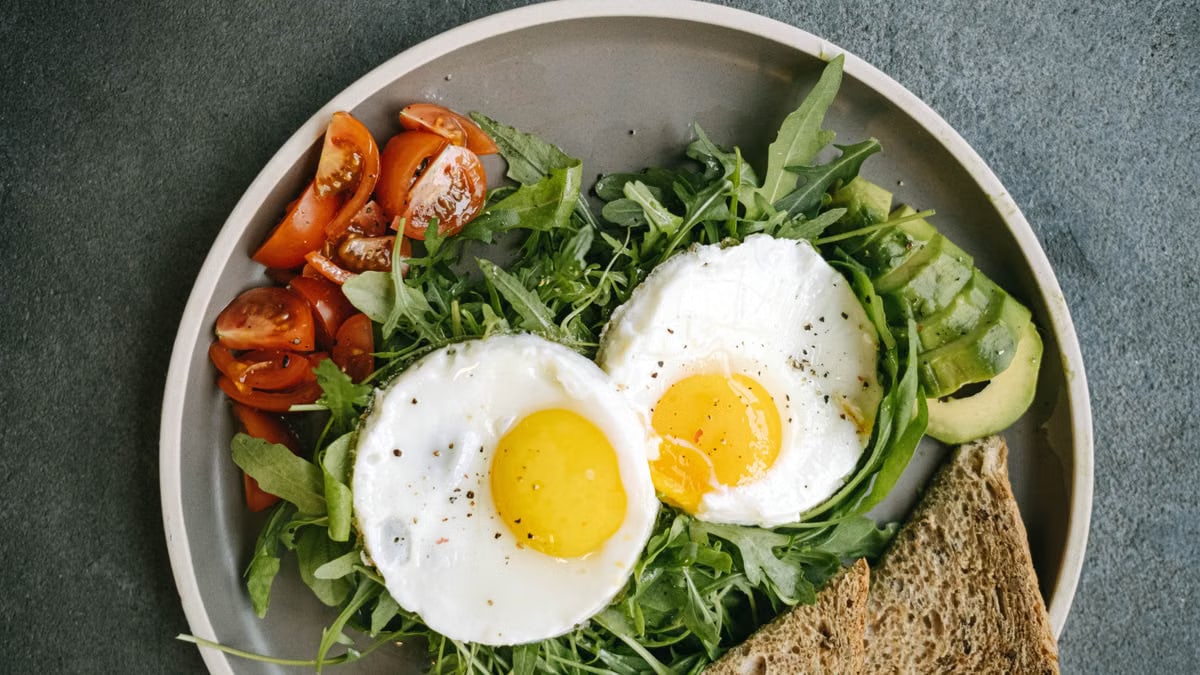 A delicious flat lay of a nutritious breakfast featuring eggs, avocado, and tomatoes.
